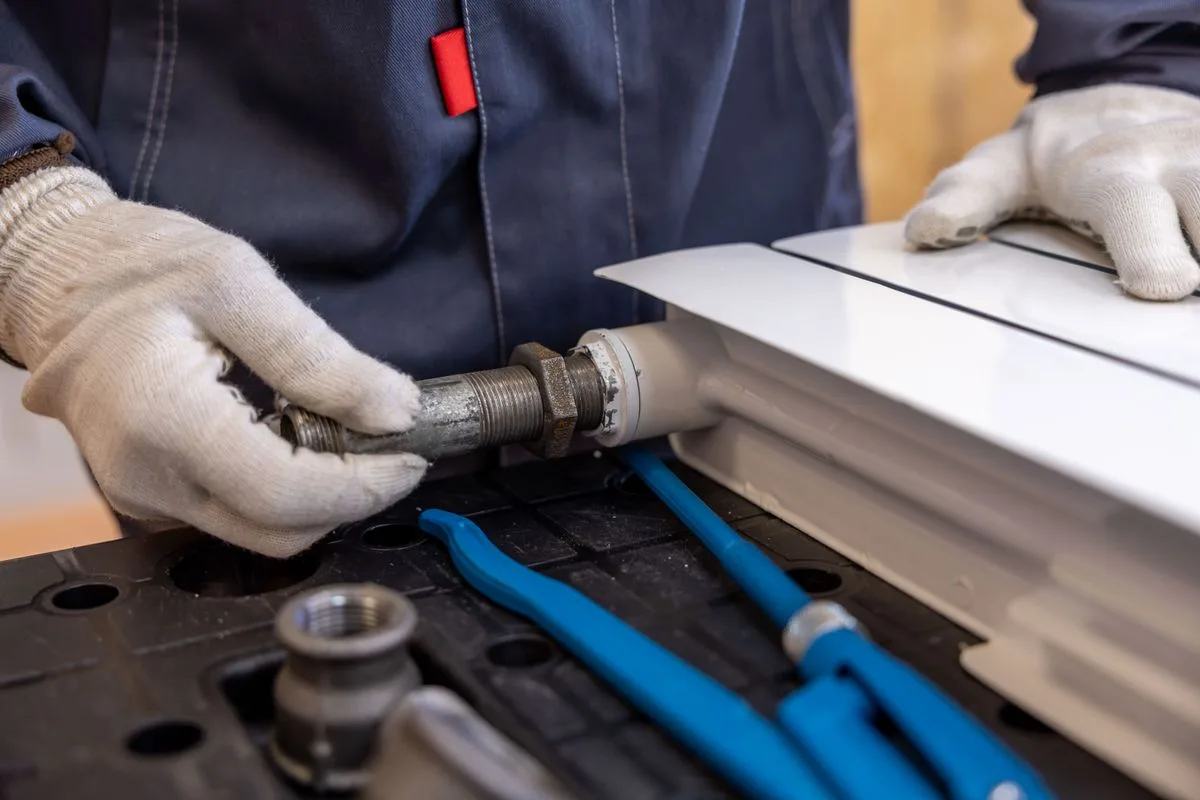 Illustrative category photo of a plumber fitting a radiator pipe