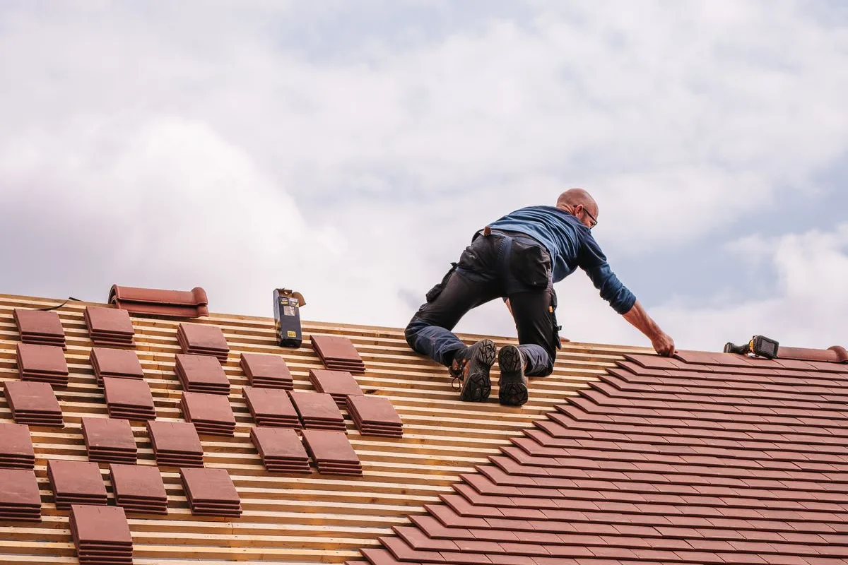 Illustrative category photo of a roofer installing shingles on a residential roof